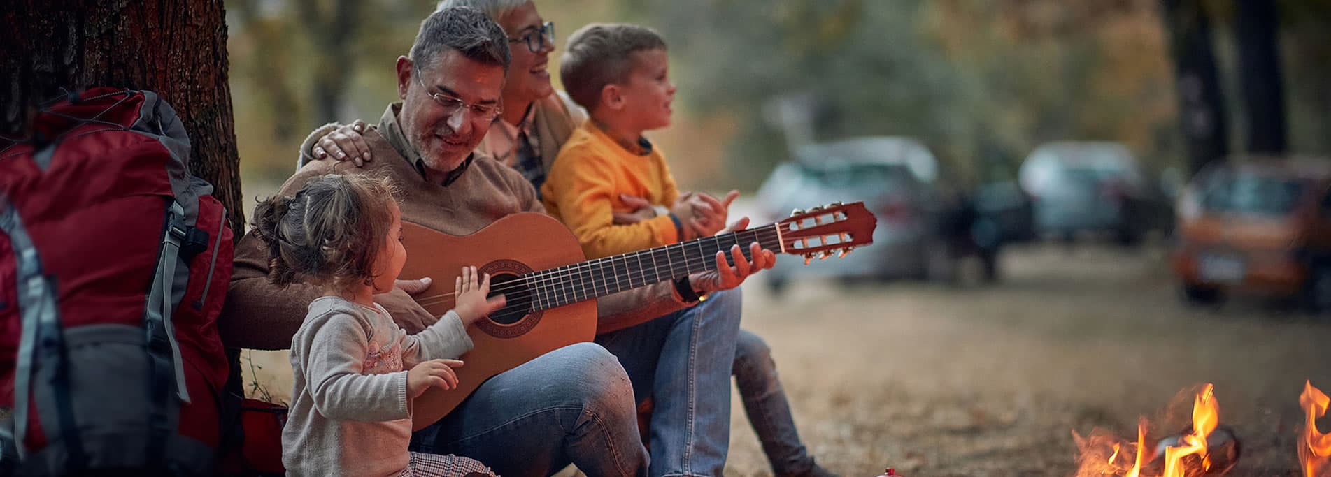 How to invest for retirement, grandparents enjoying grandchildren around a camp fire playing guitar.